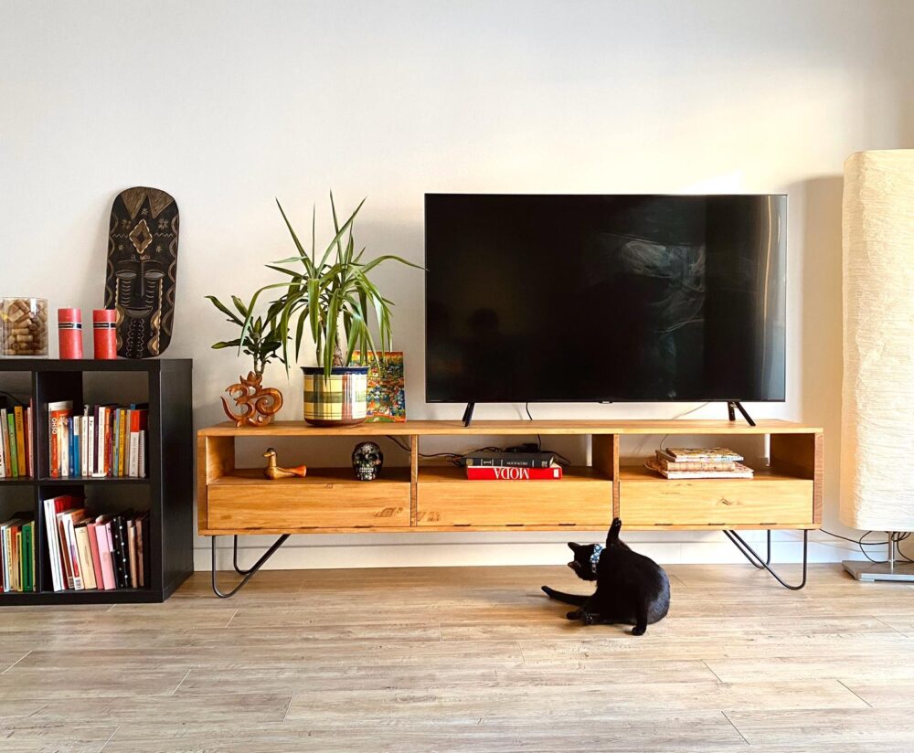 Mueble de tv en madera maciza Grövlan con 2 patas en acero macizo estilo hairpin con 3 estantes en un fondo juvenil blanco