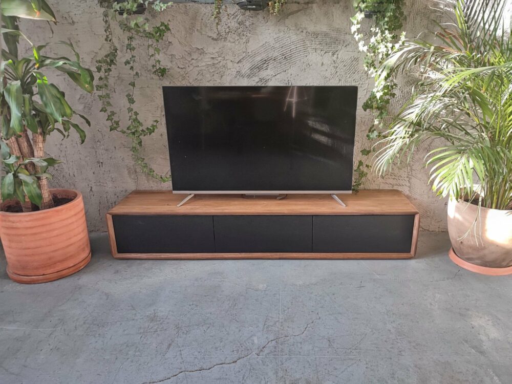 Mueble de tv en madera maciza Vela con cajones sin tirador utilizando unas guías de bolas tipo Push en un fondo gris fino